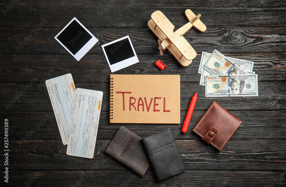 Flat lay composition with different tourist objects and word TRAVEL on wooden background