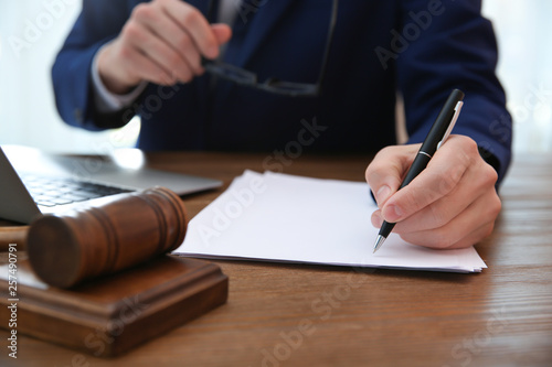 Notary working with papers and judge gavel on table, closeup. Law and justice concept
