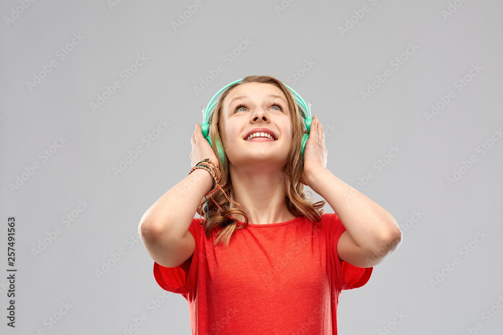 music, technology and people concept - happy teenage girl in headphones and red t-shirt over grey background music, technology and people concept - happy teenage girl in headphones and red t-shirt over grey background