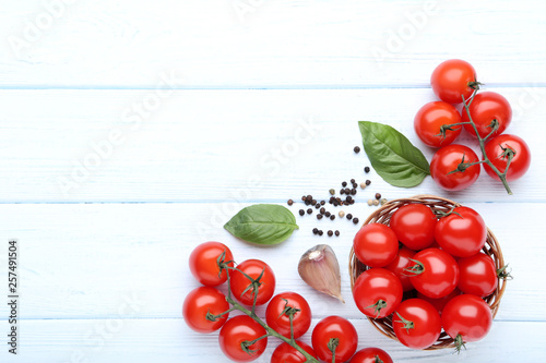 Cherry tomatoes with basil leafs, garlic and pepper on wooden table