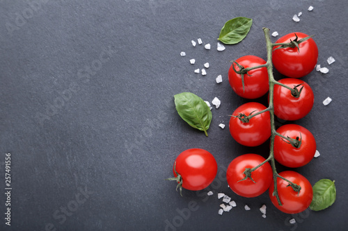 Cherry tomatoes with basil leafs and spices on black background