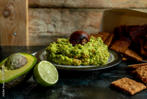 green, naturally made traditional guacamole surrounded by fresh ingredients and nachos