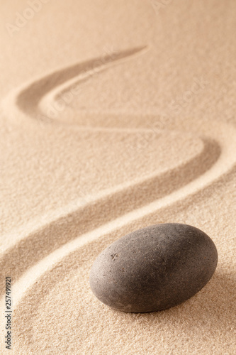 black round zen meditation stone for focus and concentration in Japanese sand garden. Textured background with copy space for mindfulness or spa wellness.