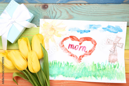 Greeting card for Mothers Day with gift box and yellow tulips on wooden table