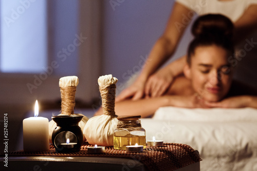 Woman relaxing in spa salon with herbal bags on wooden tray