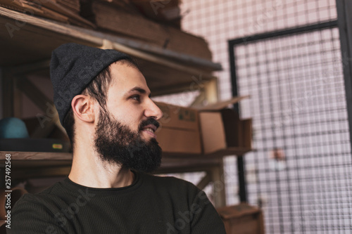 Portrait of a handsome typographer standing at the printing manufacturing stock with shelves where photographic materials, paper, and dissipative material are stored photo