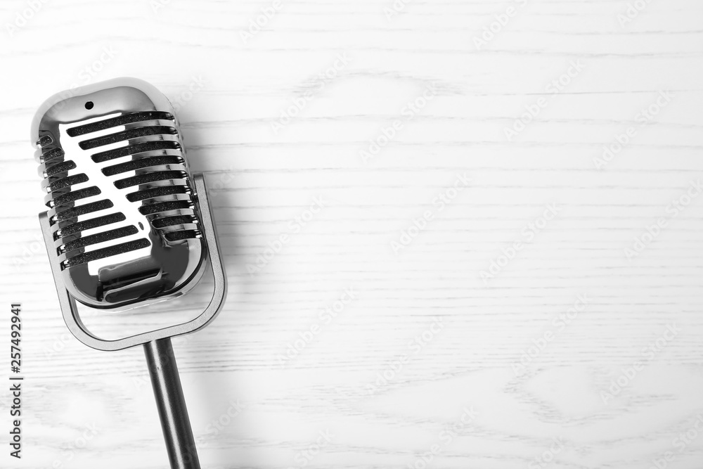 Fototapeta premium Retro microphone on wooden background, top view with space for text