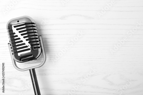 Retro microphone on wooden background, top view with space for text