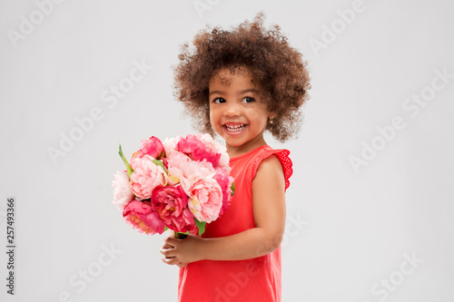 childhood and people concept - happy little african american girl with flowers over grey background