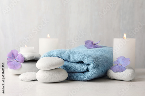 Composition with zen stones, towel and candles on table against light background