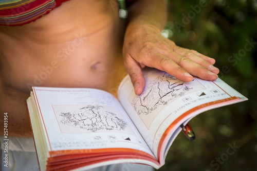Mid section of a female climber looking at a guidebook