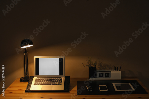 Dark room interior with laptop and devices on table. Space for text