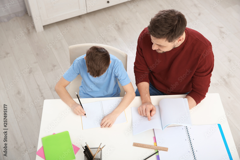 Dad helping his son with homework in room, above view