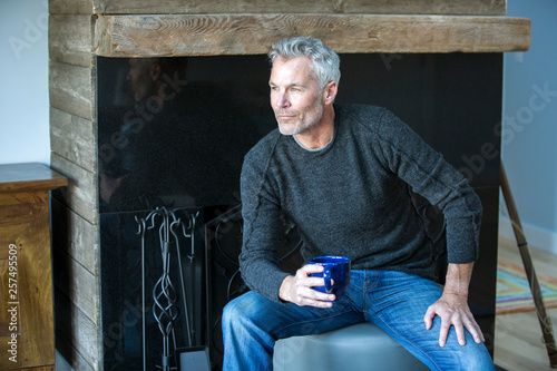 Adult man sitting in front of fireplace, Orleans, Massachusetts, USA photo