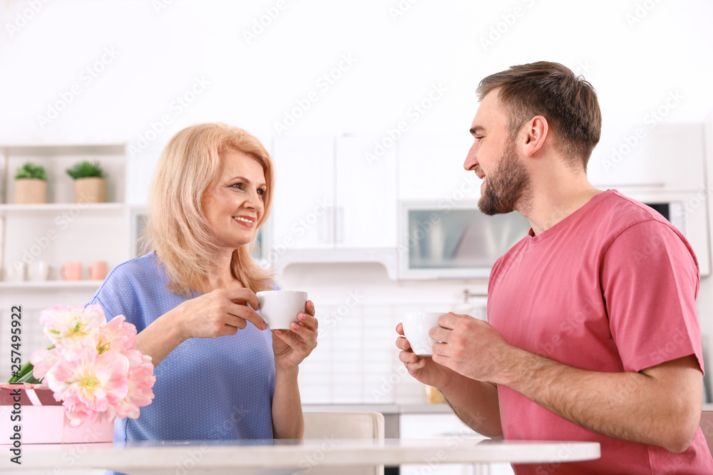 Young man and his mature mom having breakfast in kitchen. Happy Mother's Day Young man and his mature mom having breakfast in kitchen. Happy Mother's Day