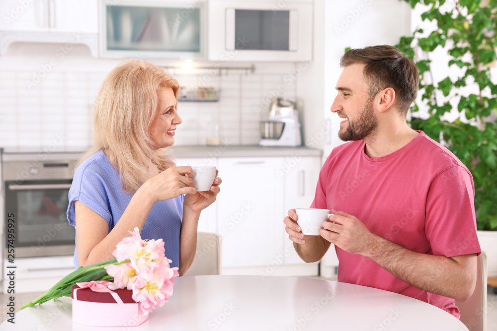 Young man and his mature mom having breakfast in kitchen. Happy Mother's Day Young man and his mature mom having breakfast in kitchen. Happy Mother's Day