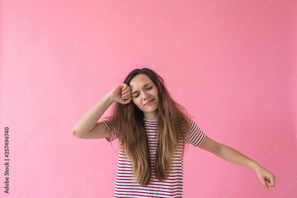 Beautiful young sleepy girl with disheveled hair and closed eyes on a pink background in the morning. Beautiful young sleepy girl with disheveled hair and closed eyes on a pink background in the morning.