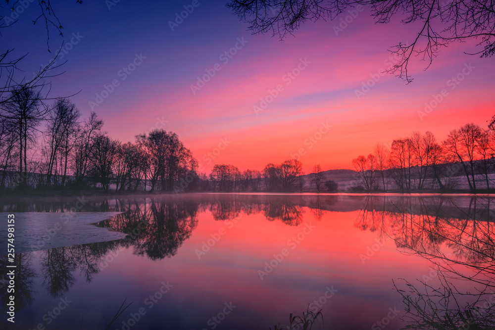 Beautiful landscape shot on a lake in winter just before the sunrise. Partly frozen and beautiful red sky. great reflection