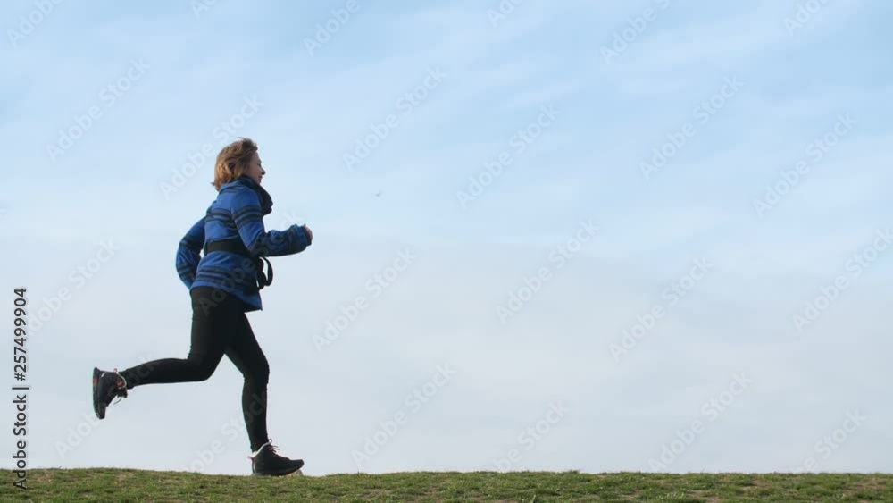 Optimistic blonde woman running and smiling in a green lawn in spring in slo-mo Optimistic blonde woman running and smiling in a green lawn in spring in slo-mo