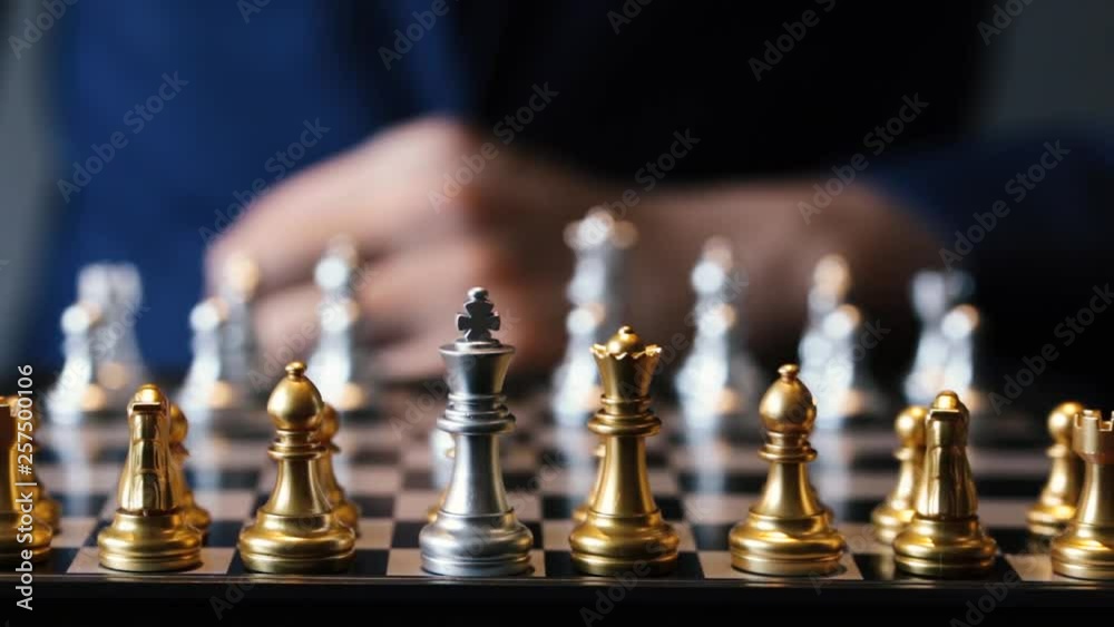 Unrecognizable male in suit making a move in chess play against gray background Unrecognizable male in suit making a move in chess play against gray background