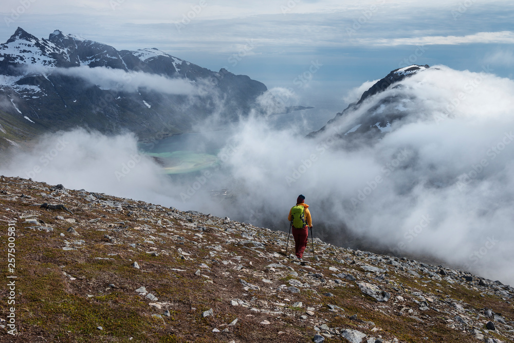 Hiker on mountain side watching mountains and valley Hiker on mountain side watching mountains and valley