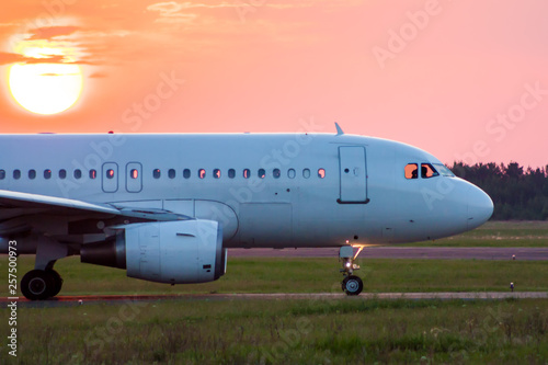 Close-up taxiing a white passenger airplane against the setting sun