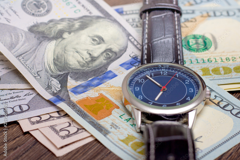 The watch is lying on dollars. Time to earn money. Time is money_ The watch is lying on dollars. Time to earn money. Time is money_