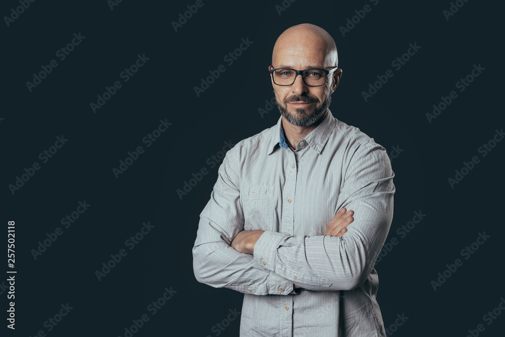 Serious middle-aged man with a smile dressed in casual poses on a dark gray background Serious middle-aged man with a smile dressed in casual poses on a dark gray background