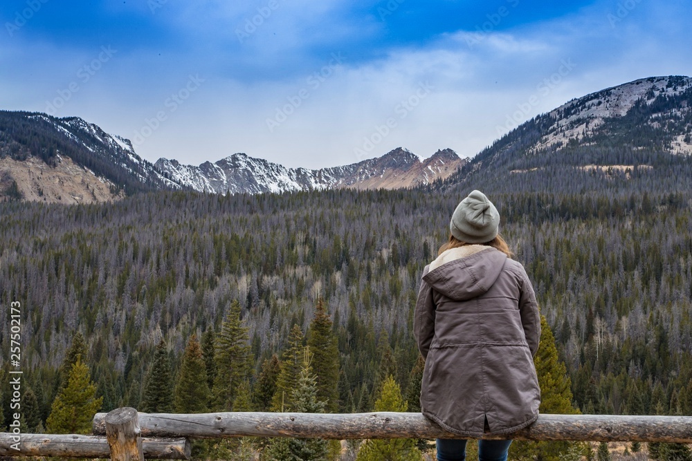 Woman Sitting on Fence Viewing Rocky Mountains