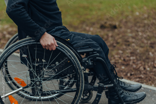 Close-up of male hand on wheel of wheelchair during walk in park