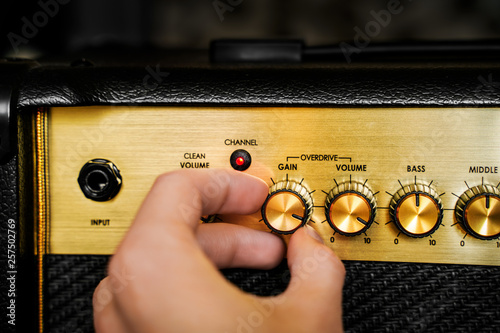 Guitar electric amplifier. Hand turning volume control knob up to the max. Rock music overdrive effect photo