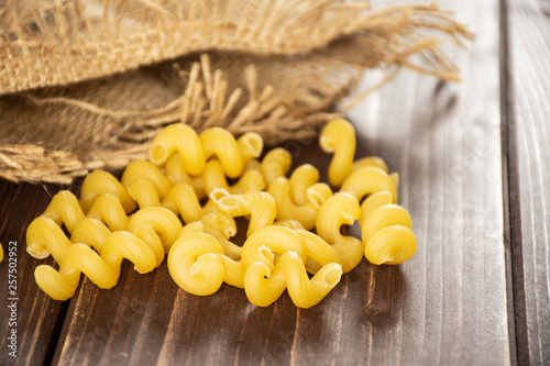 Lot of whole pasta cavatappi in a jute bag on brown wood photo