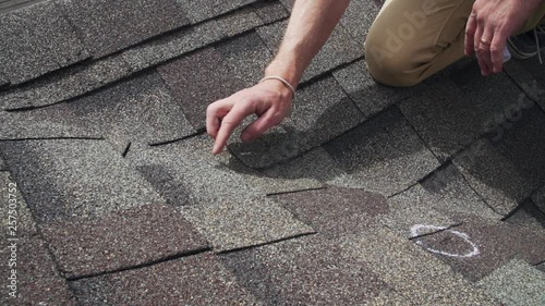 Roof hail damage inspection with chalk circles marking damaged shingles photo