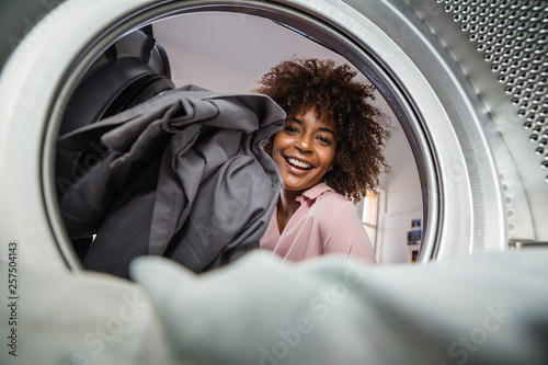 Fotografia Young black African American woman holding a basket of clothes to be washed in a