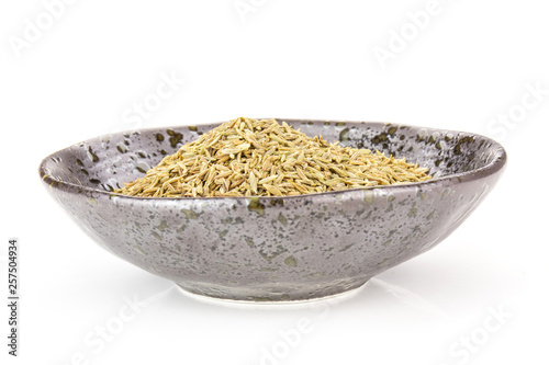 Lot of whole roman caraway seeds closeup in a grey ceramic bowl isolated on white background