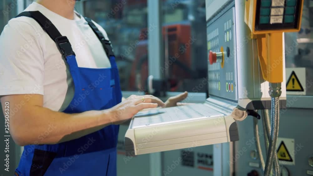 Male worker is operating a console in the factory Male worker is operating a console in the factory