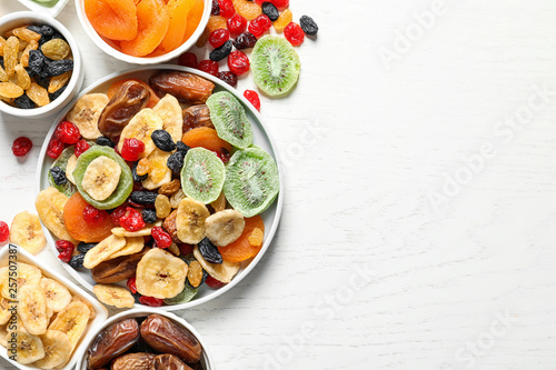 Fototapeta Naklejka Na Ścianę i Meble -  Bowls of different dried fruits on wooden background, top view with space for text. Healthy lifestyle