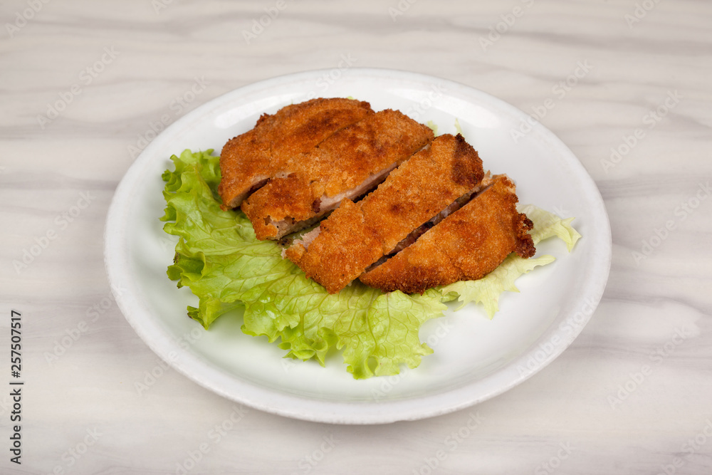Fried meat cutlet in breadcrumbs sliced and green leaf lettuce. Fried meat cutlet in breadcrumbs sliced and green leaf lettuce.