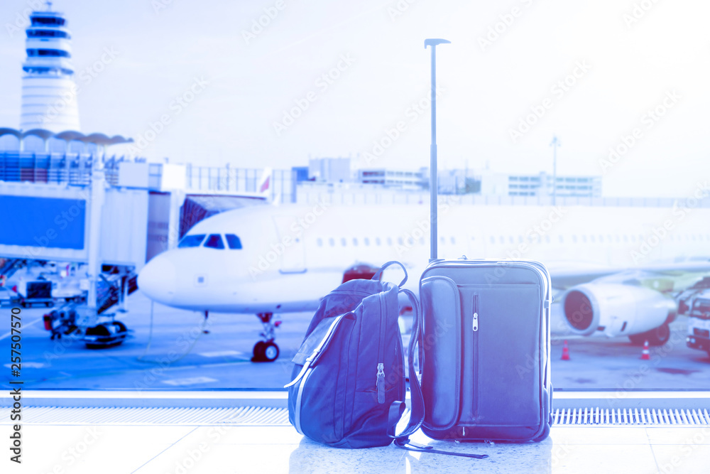 Business man suitcase and bag against air plane in the background in airport terminal during sunset. Concept of business trip and travel. Blue toned Business man suitcase and bag against air plane in the background in airport terminal during sunset. Concept of business trip and travel. Blue toned