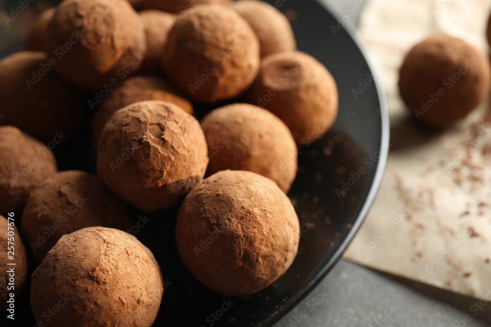 Plate with chocolate truffles on grey table, closeup Plate with chocolate truffles on grey table, closeup