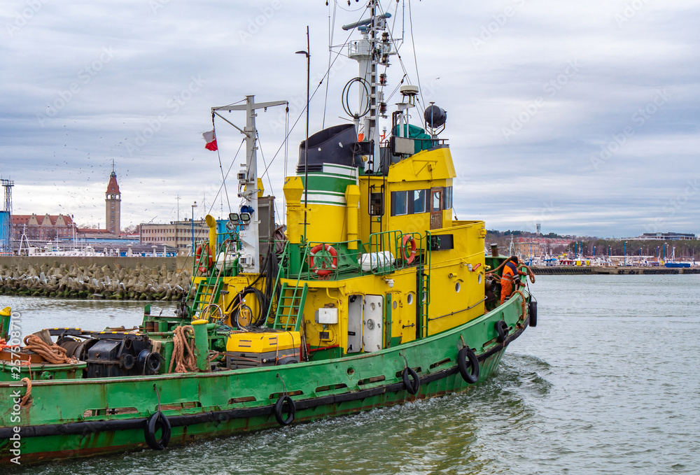 Tug boat, yellow-green color, entering the harbour.