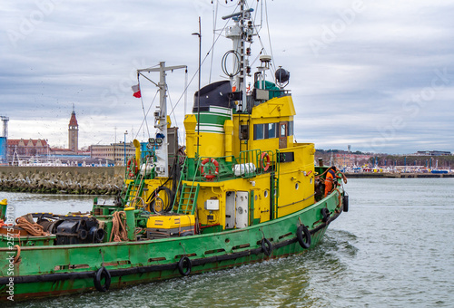 Tug boat  yellow-green color  entering the harbour.