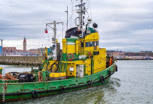 Obraz na płótnie Tug boat, yellow-green color, entering the harbour. w salonie