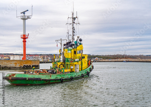 Obraz na płótnie Tug boat, yellow-green color, entering the harbour. w salonie