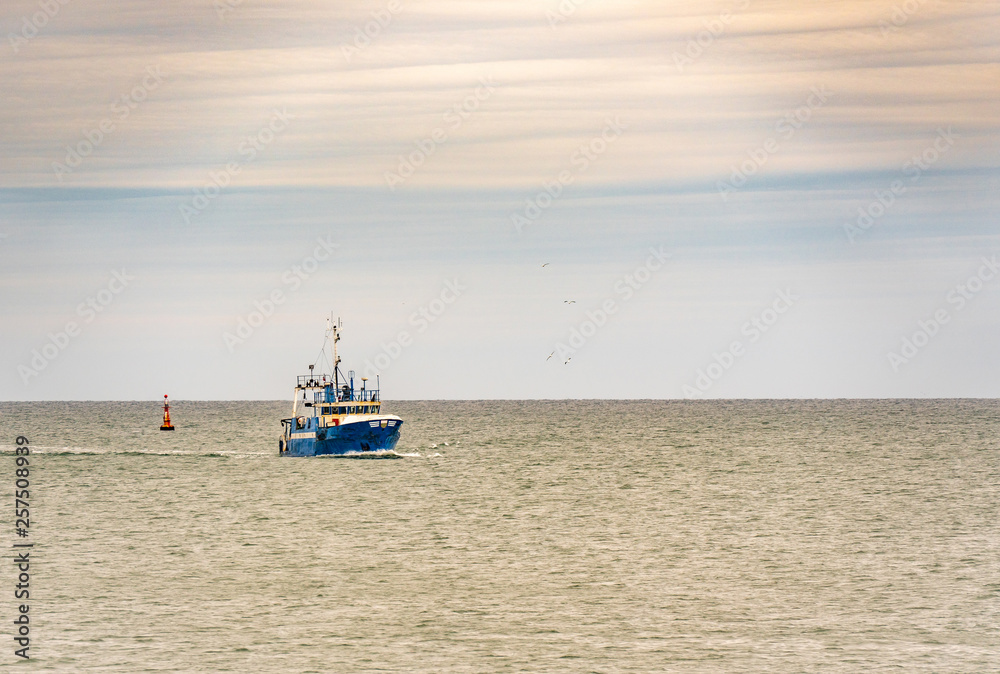 Small single fishing boat at the open sea with scenic sky.