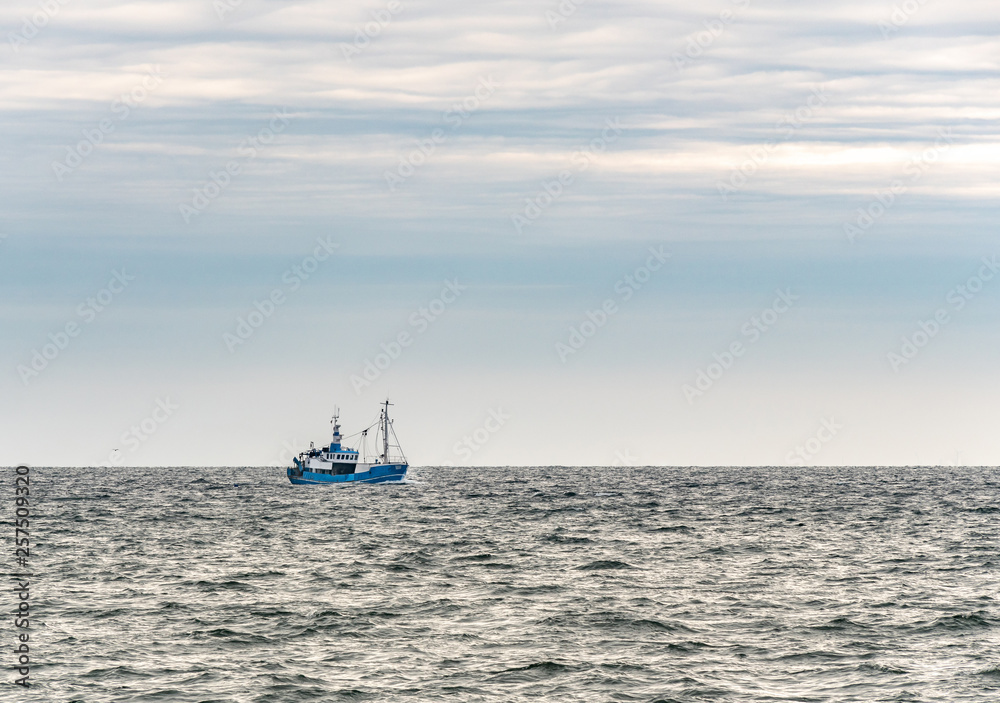 Small single fishing boat at the open sea with scenic sky.