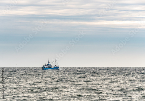 Obraz na płótnie Small single fishing boat at the open sea with scenic sky. w salonie