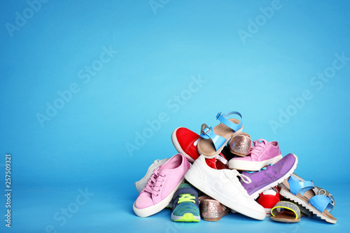 Heap of different shoes on color background. Space for text