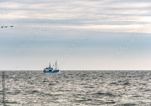 Obraz na płótnie Small single fishing boat at the open sea with scenic sky. w salonie
