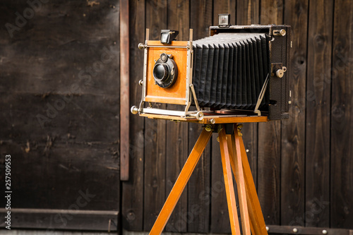 An old large format camera on a wooden tripod.